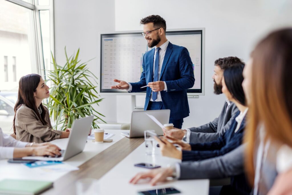 Workplace Stress: The Science Behind Prevention and Early Intervention Corporate leader speaking supportively with employees, illustrating psychological safety and trust-based leadership training by Ginny Estupinian, PhD